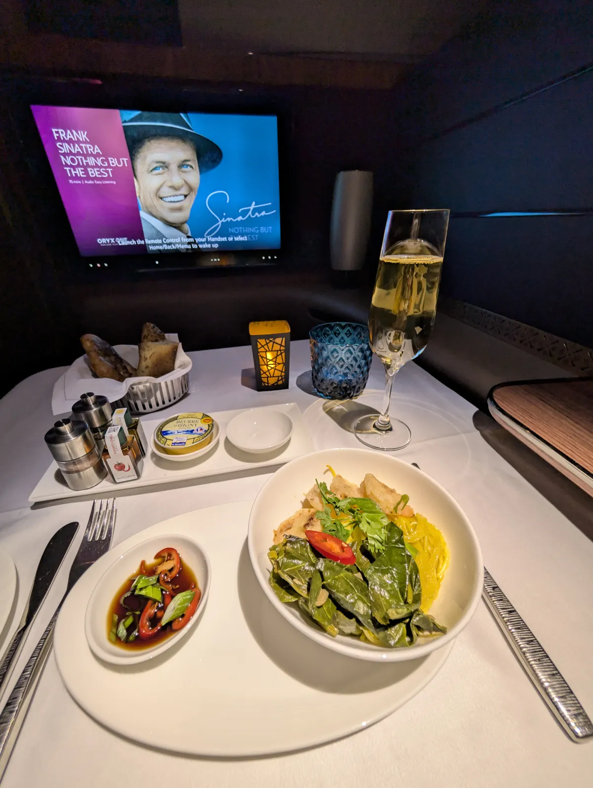 Qatar Airways First Class dinner service plate with champagne and bread basket