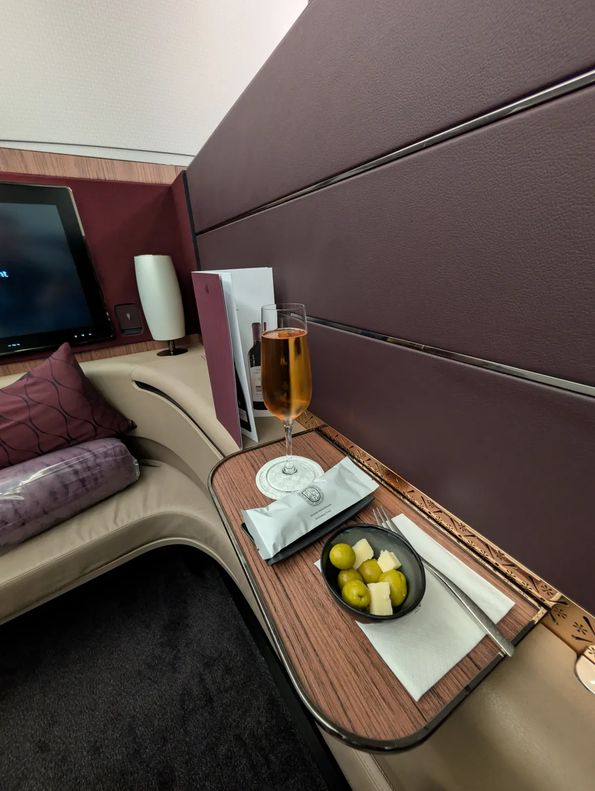 Qatar Airways First Class welcome tray with champagne, olives, and cheese