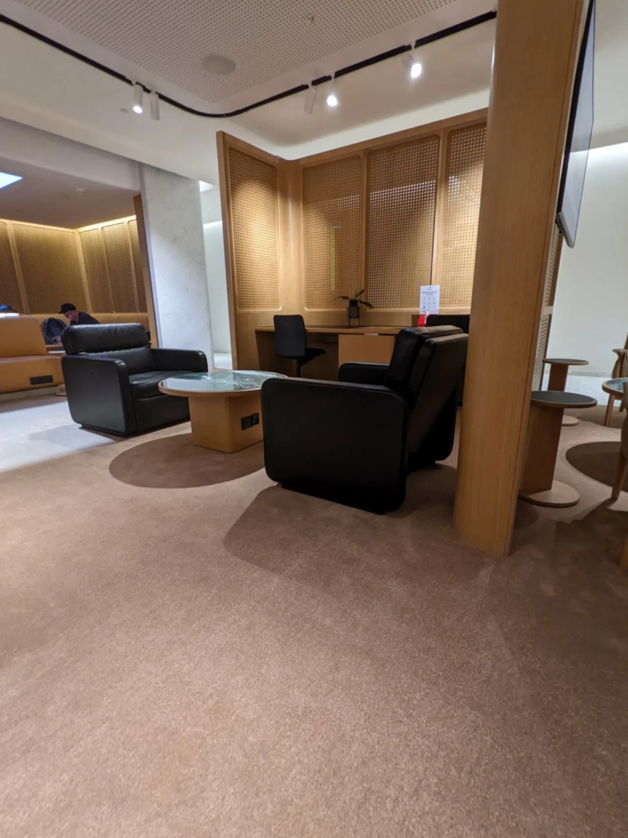 Seating area in the Qantas Singapore First Lounge at Changi Terminal 1, with black leather armchairs and wood screen dividers